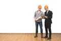 The two men in helmets stand with a tablet on the white wall background Photo