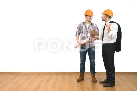 The two men in helmets stand with a tablet on the white wall background Stock Photos