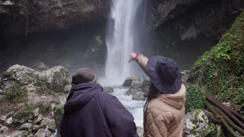 Two men hikers explore Waterfall in a rock green plants branches and stones. Stock Footage 167496358