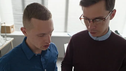 Two Men Holding Clipboard while Discussing File with Confidential Data at Office Stock Footage 313552973
