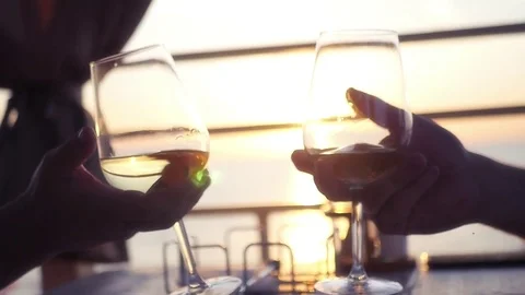 Two men holding glasses with wine in hands, against the background of the sunset Stock Footage 79782258