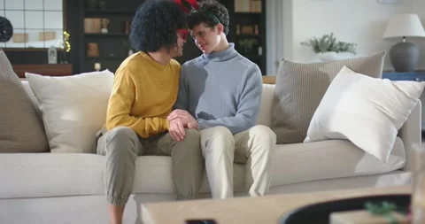 Two men holding hands on sofa, leaning, sharing gift as camera pulling focus, Stock Footage 344656452