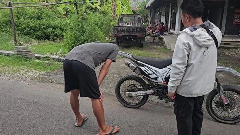 Two Men Inspecting And Discussing A Dirt Bike Parked On Street Video stock 345327698