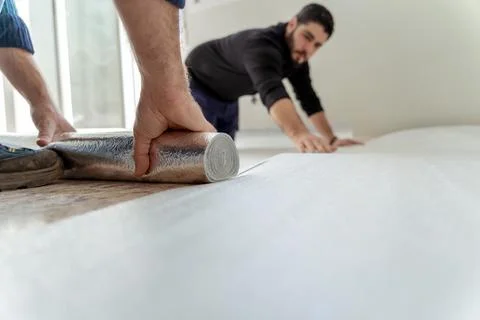 Two men installing the floor laminate for the installation of a wooden floor in Stock Photos