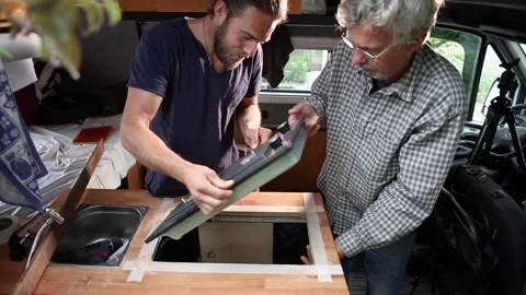 Two men installing a gas stove into a camper van Video stock 135381390