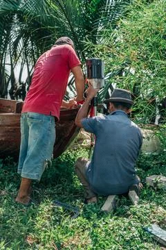 Two Men Installing Outboard Motor on Wooden Boat Stock-Fotos