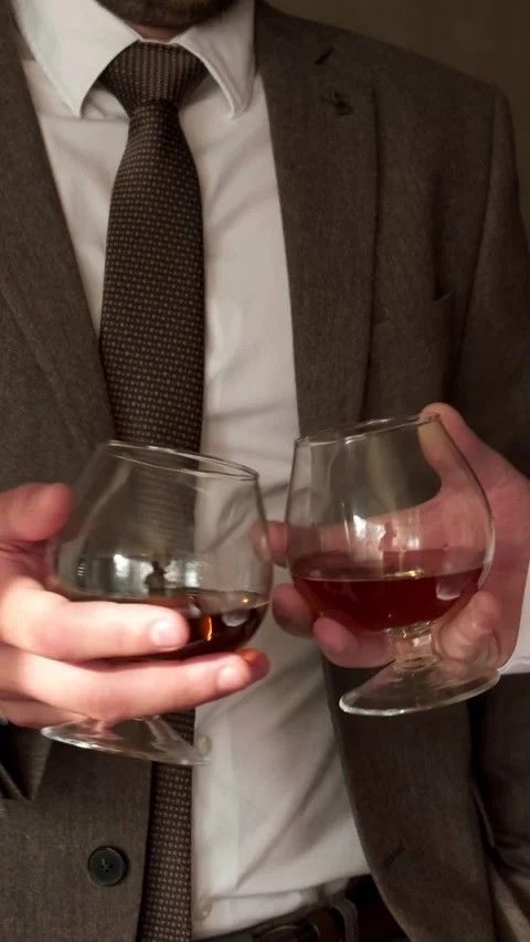 Two men in a jacket and shirt clink glasses with whiskey close-up. Slow motio Stock Footage 291953334