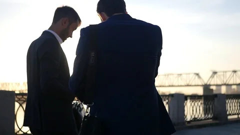 Two men in jackets are negotiating, walking down the street, holding documents Stock Footage 114601413