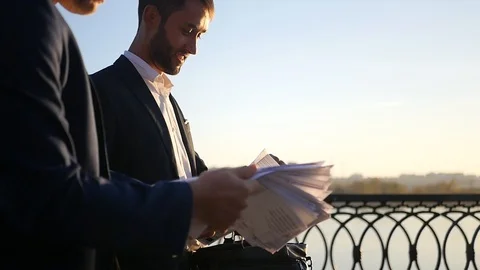Two men in jackets are negotiating, walking down the street, looking at Stock Footage 114601414