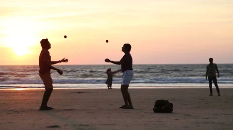 Two men juggling on a sandy beach at sunset. Stock Footage 49624043