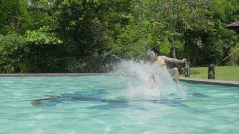 Two Men Jump Into Pool Making Big Splash in Slow Motion on Sunny Day Outdoors Stock Footage 336052604