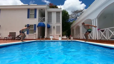 Two men jump into swimming pool Stock Footage 109106168