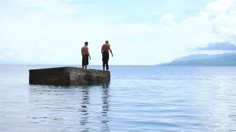 Two men jump into the water at the same time. Video stock 137687202
