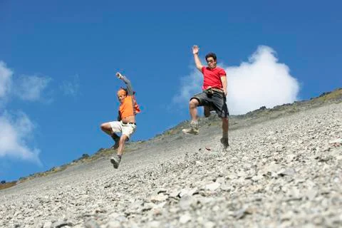 Two Men Jumping Down Scree Field Stock Photos