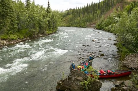Two men launch canoes beside Alaskan river rapids Foto stock