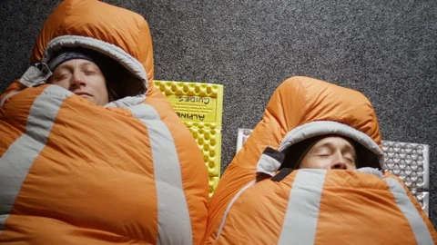 Two men laying in sleeping bags next to each other Stock Footage 116749181