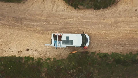 Two men lays on top of van drone shot zooming out Stock Footage 203599080