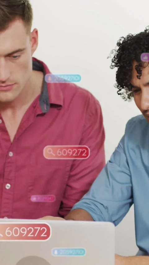 Two men leaning over laptop in tech demo, cursor clicking badge 609272 revealing Stock Footage 334604661