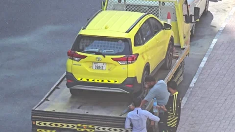 Two men load a bright yellow car onto a tow truck. Stock-Footage 311885685