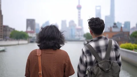 Two men looking across river at Shanghai skyline Stock Footage 346304091