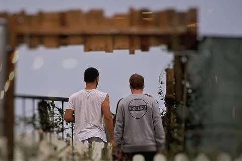Two men looking out from behind the fence Stock Photos