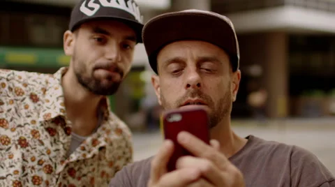 Two men looking at the phone on the street Stock Footage 61273389