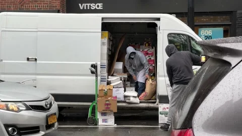 Two men with masks unloading supplies van restaurant in rain in winter in New  库存影片 147309027