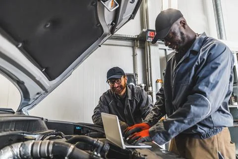 Two men mechanics completing car engine diagnostics with laptop in a repair shop Fotos de archivo