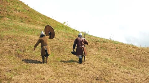 Two men in medieval warrior clothes walk away Stock Footage 283461635