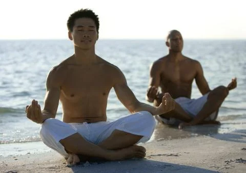 Two men meditating on beach Stock Photos