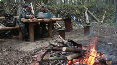 Two men in military uniform sitting at a table of logs in a transit camp in the Stock Footage 67828688