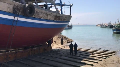 Two men near a single ship in the port of Essaouira Stock Footage 80482927
