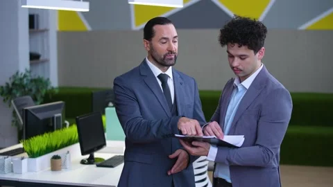 Two men in the office are discussing a report, documents Stock Footage 233717030