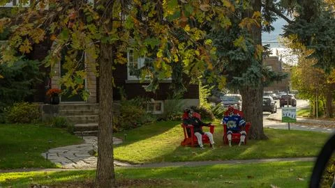Two men, one wearing a red jersey and the other in blue, are sitting on lawn Stock Photos