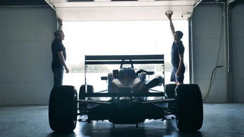 Two men open the garage and wheel a racing car out of it Stock Footage 165199121