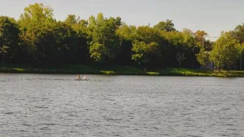 Two Men Paddling Together in a Small Boat on a Calm River in Slow Motion Stock Footage 345902210