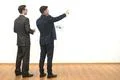 The two men with papers gesture on the white wall background Photo