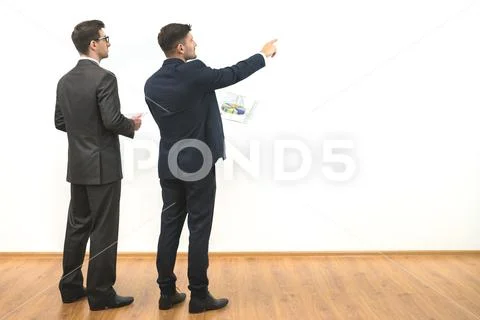 The two men with papers gesture on the white wall background Stock Photos