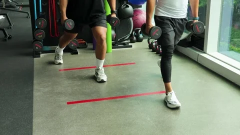 Two Men Performing Dumbbell Lunge Exercise in Gym Stock Footage 315848787