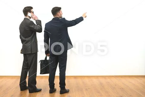 The two men phone and gesture on the white wall background Stock Photos