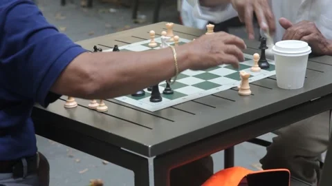 Two men playing chess outdoors at a park table Stock Footage 341323505