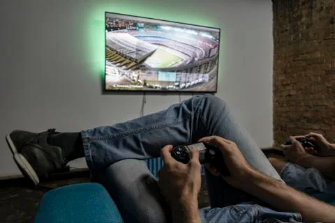 Two men playing video game. Hands holding console controller Stock Photos