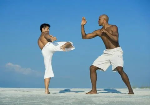 Two men practicing martial arts on beach Stock Photos