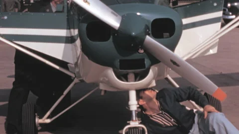 Two men prepare a small propeller plane for flight. Historical film digitized Stock Footage 168886482