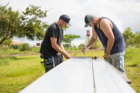 Two men preparing steel excursion for solar panel installation. Stock Photos