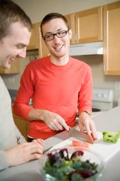 Two men preparing vegetables in kitchen together Stock Photos