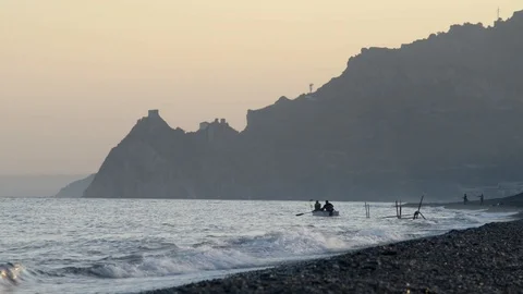 Two men put their boat in the water at sunset to go fishing Stock Footage 97761718