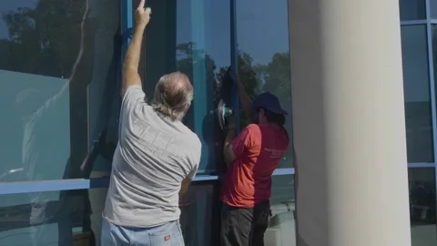 Two Men Putting in a Large Blue Glass Window Stock Footage 209289686