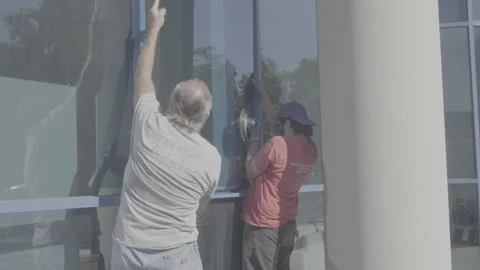 Two Men Putting in a Large Blue Glass Window - RAW Stock Footage 209289704