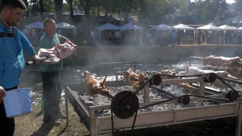 Two men putting pig on the stick at fireplace barbecue Stock Footage 96116832